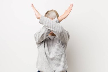 Beyaz arka planda izole edilmiş, iki kolu çapraz tutan, inkar kavramı olan genç beyaz kadın..