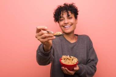 Elinde mısır gevreği kasesi tutan, doğum lekesi olan Afrikalı Amerikalı genç bir kadın.