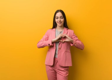 Genç, modern iş kadını elleriyle kalp şekli çiziyor.