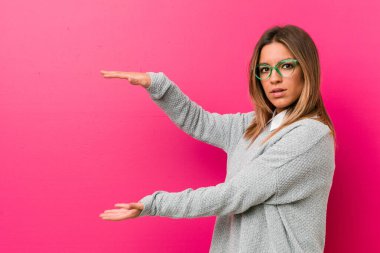 Bir duvara karşı genç otantik karizmatik gerçek insanlar kadın şok ve elleri arasında bir kopya alanı tutarak hayran.