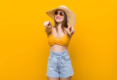 Hasır şapka takan genç beyaz kadın, yaz mevsiminde mutlu bir şekilde gülümse..