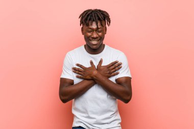 Genç Afrikalı siyahi adam gülüyor. Elini yüreğine koyuyor. Mutluluk kavramı..