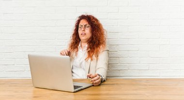 Genç kızıl saçlı, laptopuyla çalışan kıvırcık kadın yakın bir tehlike yüzünden şok oluyor.