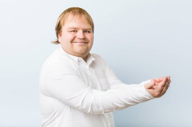 Genç otantik kızıl saçlı şişman adam bir avuç üzerinde bir kopya alanı tutan.