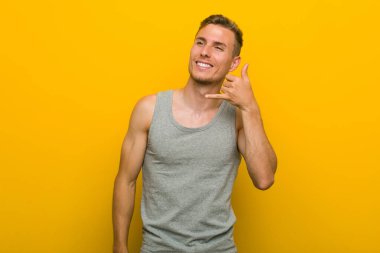 Kafkasyalı genç sporcu parmaklarıyla bir cep telefonu hareketi gösteriyor..