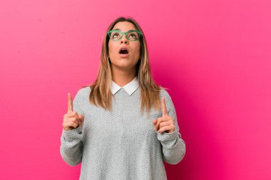 Genç, otantik, karizmatik, gerçek bir kadın. Duvara dayalı, ağzı açık, üst tarafı gösteren bir kadın..