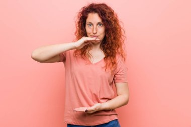 Genç, doğal ve otantik kızıl saçlı kadın iki eliyle bir şey tutuyor, ürün sunumu..