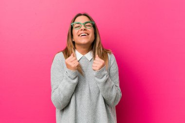 Genç otantik karizmatik gerçek insanlar kadın bir duvara karşı yumruk yükselterek, mutlu ve başarılı hissediyorum. Zafer kavramı.