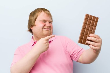 Beyaz çılgın sarışın şişman adam bir çikolata tablet tutan