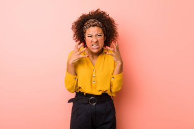 Genç Afrikalı Amerikalı kadın pembe arka planda gergin ellerle çığlık atıyor..