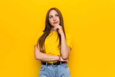 Kızıl saçlı genç bir kadın şüpheli ve kuşkulu bir ifadeyle yana bakıyor..