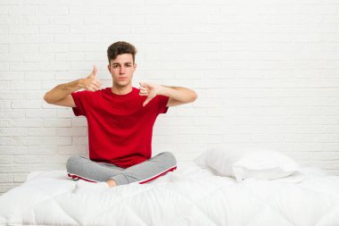 Yataktaki genç öğrenci başparmağını kaldırıyor ve baş parmağını eğiyor. Zor bir seçim.