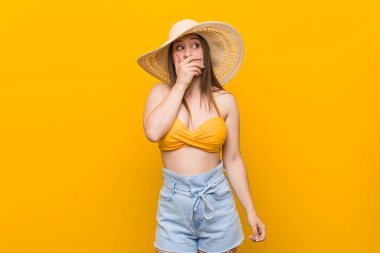 Hasır şapkalı, genç beyaz bir kadın. Yazın düşünceli görün. Ağzını elinle kapatan bir fotokopi odasına bak..