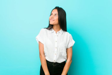 Genç İspanyol asıllı havalı kadın mavi bir duvarın karşısında amaçlarına ve amaçlarına ulaşmayı hayal ediyor.