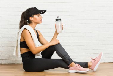 Genç Arap sportif kadın oturmuş su içiyor.