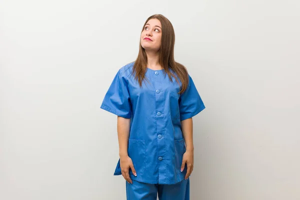 Jovem Enfermeira Mulher Contra Uma Parede Branca Sonhando Alcançar Objetivos — Fotografia de Stock
