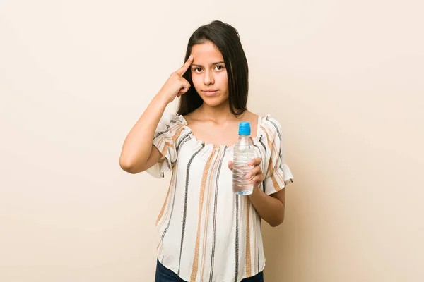 Junge Hispanische Frau Hält Eine Flasche Wasser Und Zeigt Mit — Stockfoto