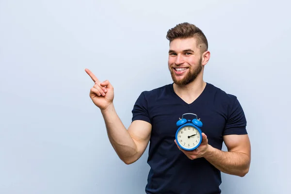 Jovem Caucasiano Segurando Despertador Sorrindo Alegremente Apontando Com Dedo Indicador — Fotografia de Stock