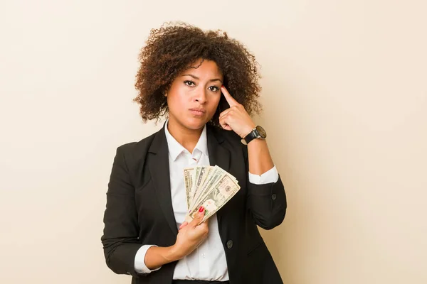 Genç Afrikalı Amerikalı Kadın Elinde Dolarlarla Tapınağını Işaret Ediyor Düşünüyor — Stok fotoğraf