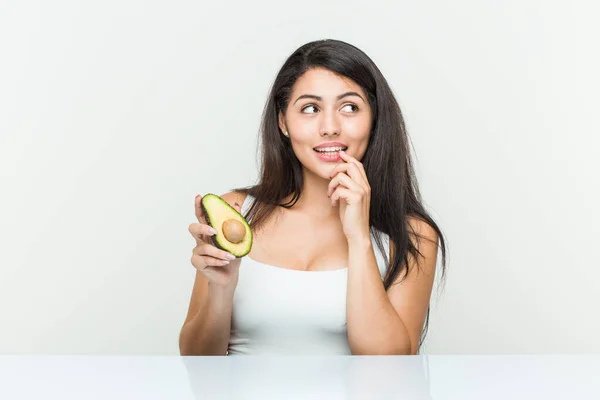 Mujer Hispana Joven Sosteniendo Aguacate Relajado Pensando Algo Mirando Espacio — Foto de Stock