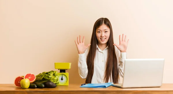 Młoda Chińska Dietetyczka Pracująca Laptopem Pokazuje Numer Rękami — Zdjęcie stockowe