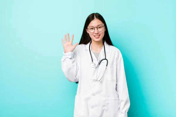 Young chinese doctor woman smiling cheerful showing number five with fingers.