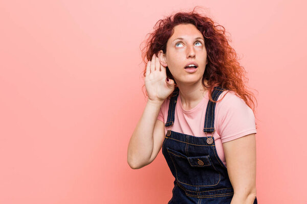 Молодая симпатичная рыжая рыжая женщина в джинсах Дунгари пытается слушать сплетни
.