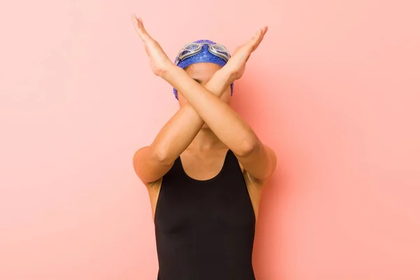 Young arab swimmer woman isolated keeping two arms crossed, denial concept.