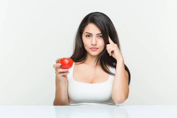 Joven Mujer Hispana Sosteniendo Tomate Señalando Sien Con Dedo Pensando —  Fotos de Stock