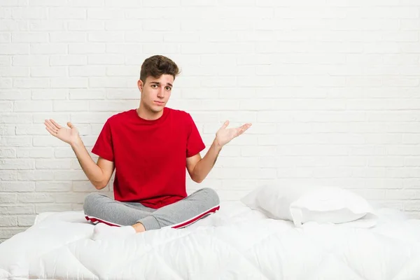 Genç Bir Öğrenci Yatakta Şüphe Içinde Omuz Silkerek Jestlerini Sorguluyor — Stok fotoğraf