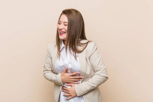 Young business woman laughs happily and has fun keeping hands on stomach.