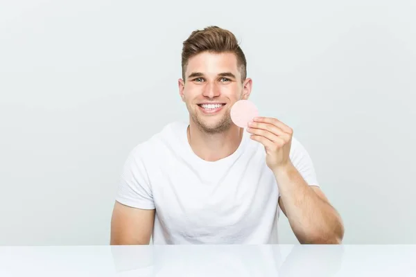 Joven hombre caucásico usando una esponja facial . —  Fotos de Stock