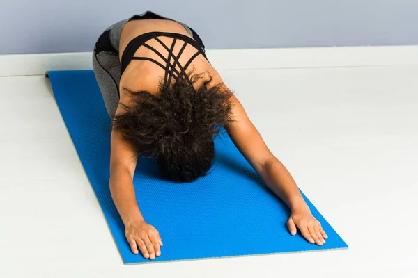 Young african american sporty woman practicing yoga lying using a mat