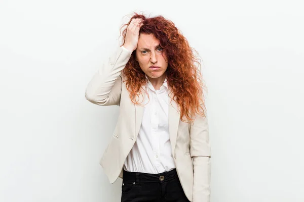 Young natural redhead business woman isolated against white background being shocked, she has remembered important meeting.