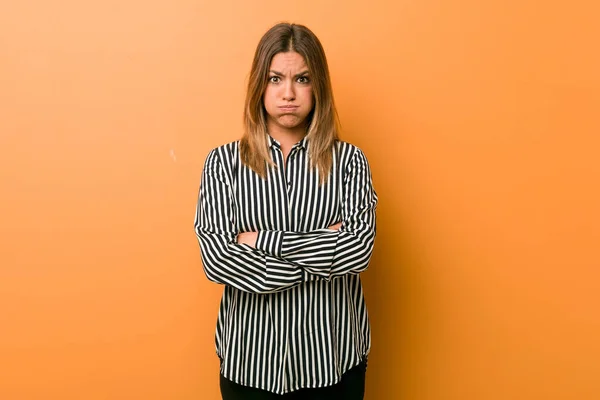 Young authentic charismatic real people woman against a wall blows cheeks, has tired expression. Facial expression concept.