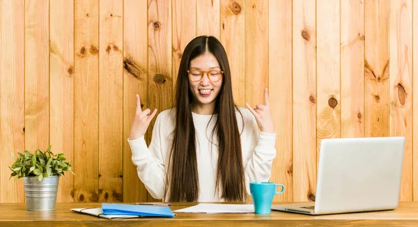 Jovem Chinesa Estudando Sua Mesa Mostrando Gesto Rocha Com Dedos — Fotografia de Stock