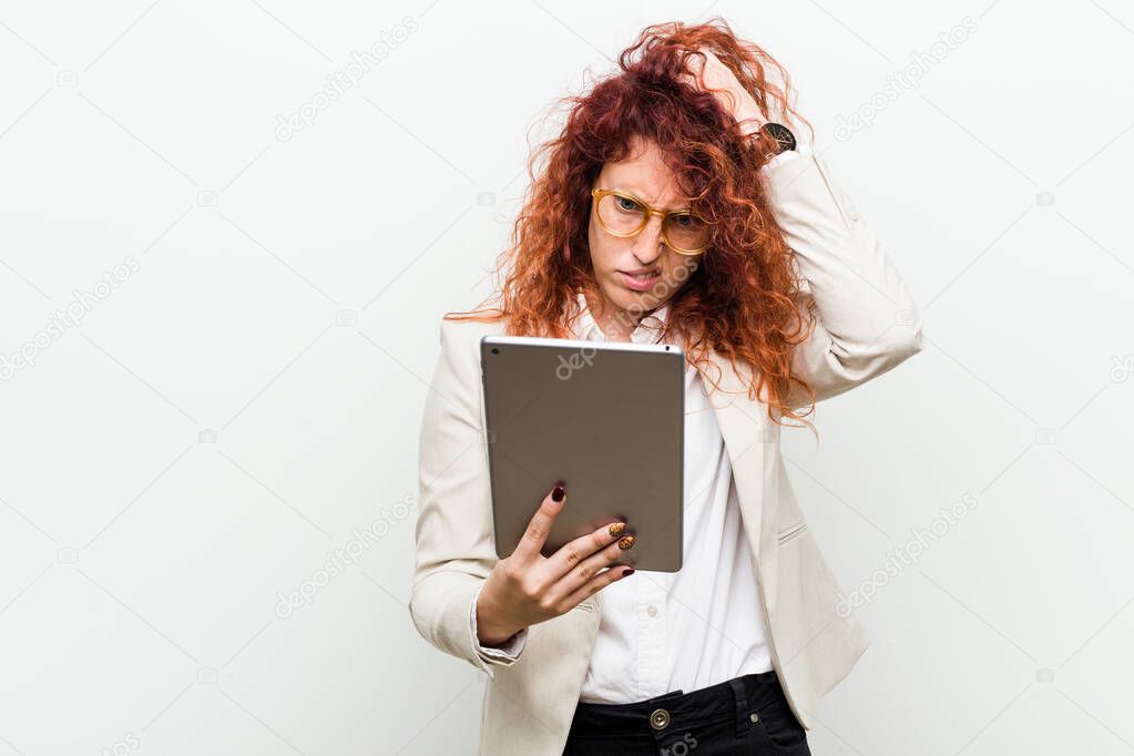 Young caucasian business redhead woman holding a tablet being shocked, she has remembered important meeting.