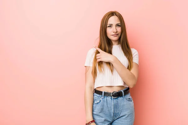 Mladá Zrzka Zrzka Žena Růžové Stěny Usmívá Ukazuje Stranou Něco — Stock fotografie