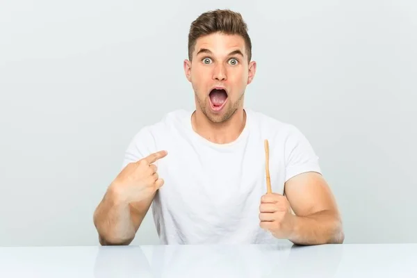 Young Man Holding Toothbrush Surprised Pointing Himself Smiling Broadly — Stock Photo, Image