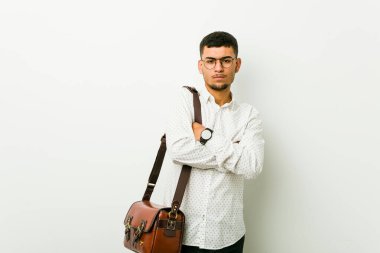 Genç Latin asıllı sıradan bir iş adamı hoşnutsuzca kaşlarını çatıyor, kollarını kavuşturuyor..