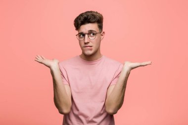 Kafası karışık, genç, beyaz bir adam bir fotokopi çekmek için elini kaldırıyor..