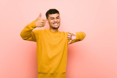 Genç İspanyol adam başparmak yukarı ve başparmak aşağı gösteren, zor kavramı seçin