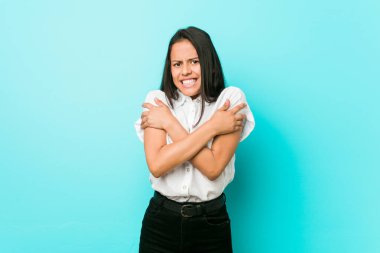 Genç, İspanyol asıllı, havalı bir kadın, mavi bir duvara yaslanmış. Düşük ateş ya da hastalık yüzünden soğuyor..