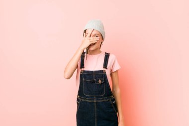 Genç kadın kameraya parmaklarıyla göz kırpıyor, utanarak yüzünü kapatıyor..