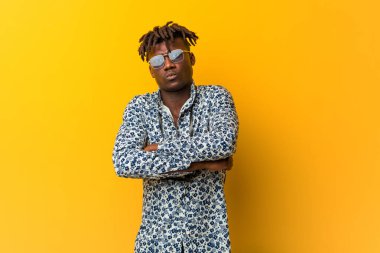 Tatil giyen genç siyah Rasta 'lı adam alaycı bir ifadeyle kameraya bakarken mutsuz görünüyor..