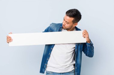 Genç Güney Asyalı adam elinde beyaz bir levha tutuyor..
