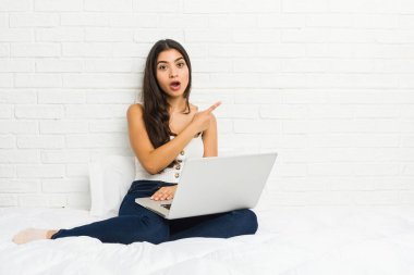 Genç Arap kadın dizüstü bilgisayarıyla yan tarafı işaret ediyor.