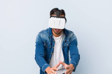 Genç Güney Asyalı adam sanal gerçeklik gözlükleriyle oynuyor.