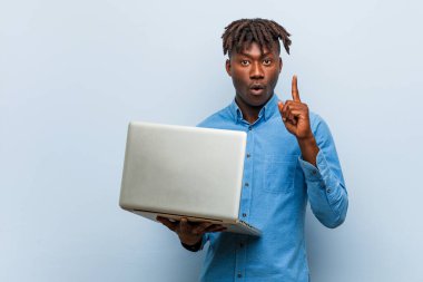 Genç Rasta siyahi adam dizüstü bilgisayar tutuyor. Harika bir fikri var. Yaratıcılık kavramı..