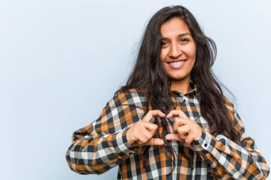 Genç, havalı Hintli kadın gülümseyerek kalp şeklini elleriyle gösteriyor..